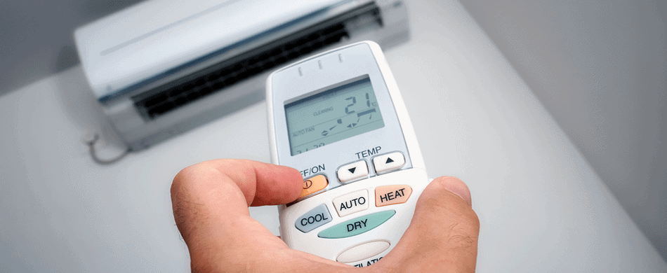Hand holding a remote control, adjusting settings for a wall-mounted air conditioning unit.