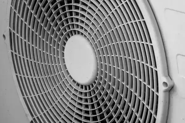 Close-up view of a circular metal fan grill with evenly spaced bars, part of a heat pump repair system in Goshen NY.