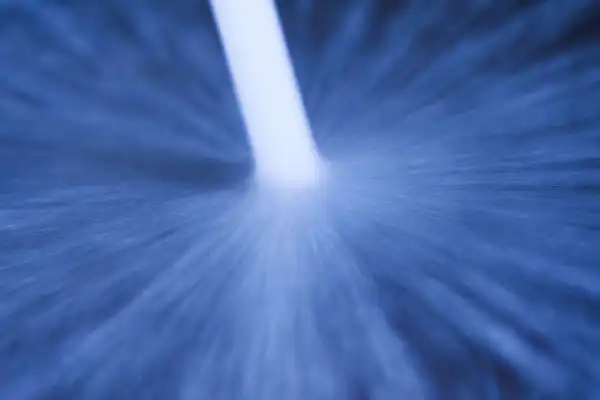 A close-up image of a stream of water from a Hydro Jetting Service spraying down onto a blue surface, causing water to splash and spread outward in all directions.