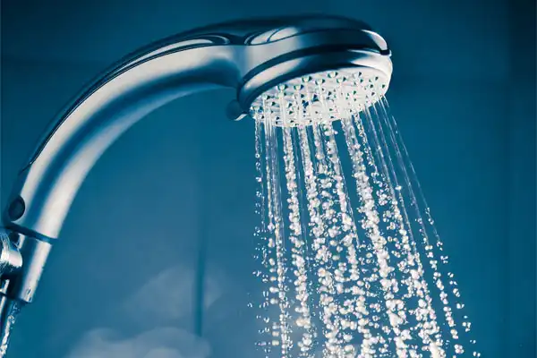 Close-up of a showerhead spraying water streams in a bathroom, ideal after expert Tankless Water Heater Repair in Goshen NY.